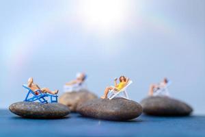 Gente en miniatura tomando el sol en una playa, concepto de verano foto