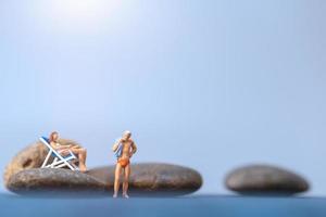 Gente en miniatura tomando el sol en una playa, concepto de verano foto