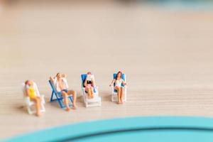 Gente en miniatura tomando el sol en una playa, concepto de verano foto