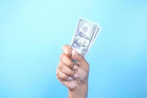 hombre sosteniendo dinero en efectivo sobre fondo azul foto