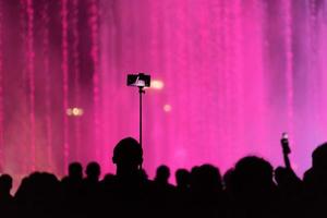 Person filming with a cell phone among group of people at a fountain in Sochi, Russia photo