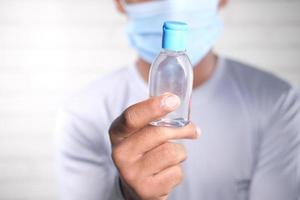 Man in face mask holding sanitizer liquid photo