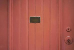 Detalle de la puerta de madera roja con placa de latón en el medio foto