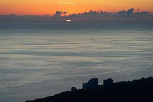 Orange cloudy sunset over the sea in Sochi, Russia photo