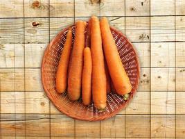 Zanahorias en una cesta de mimbre sobre un fondo de mesa de madera