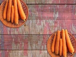 Zanahorias en dos cestas de mimbre sobre un fondo de mesa de madera