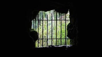 Cascada detrás de vallas de hierro en una cueva oscura