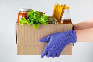 A woman volunteer is holding a donation box with foodstuffs. Delivery of necessary food during an epidemic. photo