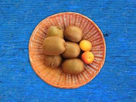 Kiwis and apricots in a wicker basket on a wooden table background