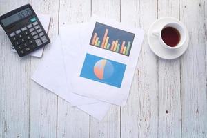 Financial graph, calculator, and notepad on table photo