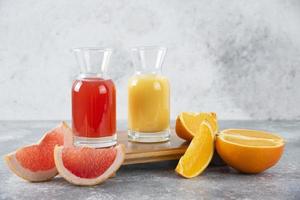 Dos vasos de pomelo y jugo de naranja sobre un fondo de piedra foto