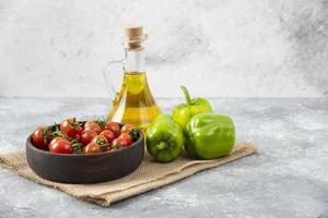 Verduras frescas maduras y una botella de aceite colocada sobre una superficie de tela de saco foto