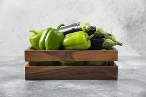 Caja de madera llena de verduras frescas maduras colocadas sobre un fondo de piedra foto