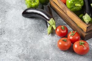 Caja de madera llena de verduras frescas maduras colocadas sobre un fondo de piedra foto