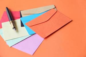 Colorful envelopes and fountain pen on orange background