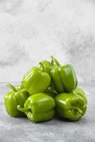 Fresh green bell peppers placed on a stone background photo