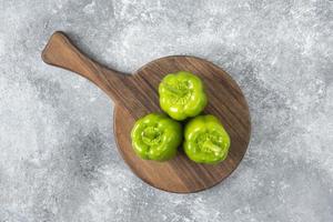Fresh green bell peppers placed on a wooden round board photo