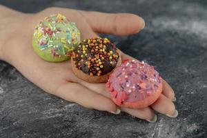 Mano de mujer sosteniendo coloridos donuts dulces con chispitas foto