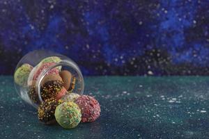 un frasco de vidrio lleno de pequeñas rosquillas de colores