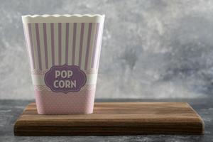 A wooden cutting board with a bucket of popcorn photo