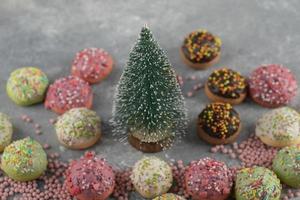 donas pequeñas y dulces de colores con chispas y un adorno navideño foto