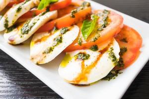 Ensalada de tomate y queso mozzarella en placa blanca. foto