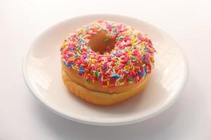 Donut with sprinkles on white plate on white background photo