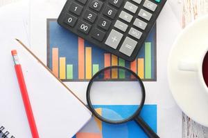 Financial graph, magnifying glass, and notepad on table photo