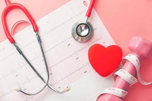 Heart health concept with pink dumbbell and stethescope photo