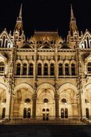 El parlamento húngaro en Budapest sobre el Danubio en las luces nocturnas de las farolas foto