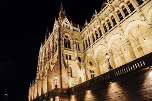 El parlamento húngaro en Budapest sobre el Danubio en las luces nocturnas de las farolas foto