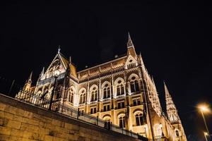 El parlamento húngaro en Budapest sobre el Danubio en las luces nocturnas de las farolas foto