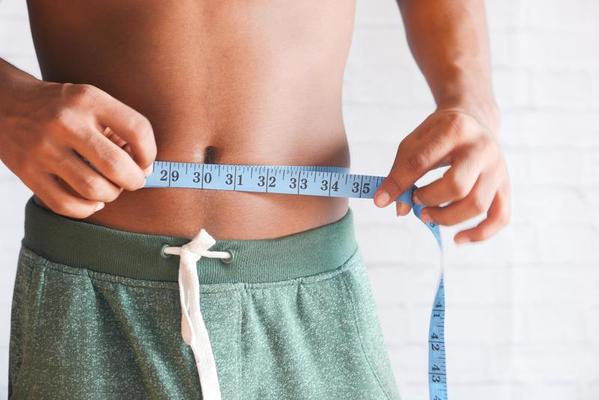 Man measuring his waist with a tape measure 2246454 Stock Photo at Vecteezy