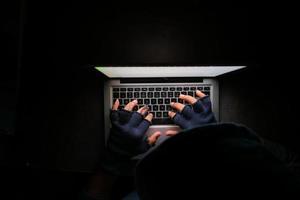 Top view of person in black hood using a laptop at night photo