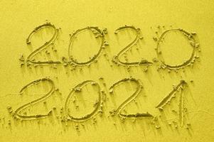 Inscription on the gold sand 2020 and 2021, toned in trend color of the year 2021 photo