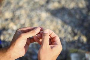 Man's hands tying a fishing line on a fishing hook photo