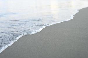 Blurred wave of the sea on the evening sand beach photo