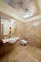 Modern beige restroom with a toilet, sink, mirror, and bidet photo