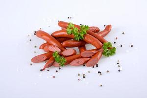Smoked pork sausages, grill sausages, and scattered pepper isolated on a white background photo