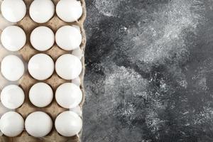 Raw chicken eggs in an egg box on a marble background photo