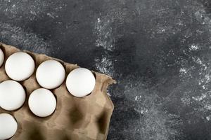 Huevos de gallina crudos en una caja de huevos sobre un fondo de mármol foto