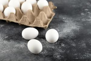 Tres huevos frescos de pollo crudo sobre un fondo de mármol