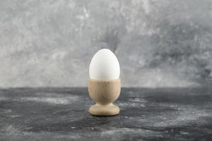 una huevera de madera con un huevo de gallina cocido foto