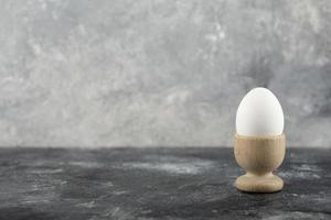 A wooden eggcup with a boiled chicken egg photo