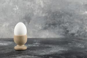 una huevera de madera con un huevo de gallina cocido foto