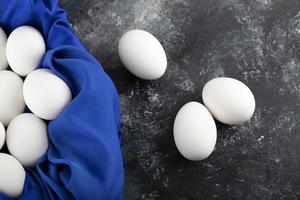 White raw chicken eggs with on a blue tablecloth photo