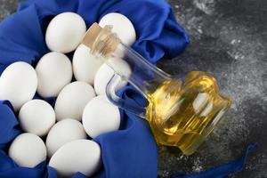 Huevos de gallina cruda blanca con una botella de aceite de vidrio foto