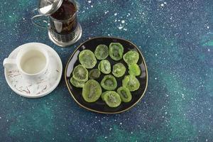 A black plate full of dried kiwi fruit and a cup of tea photo