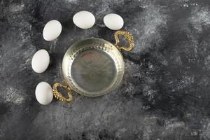 White raw chicken eggs with a saucepan