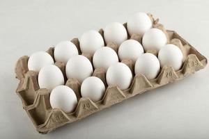 Raw chicken eggs in an egg box on a white background photo
